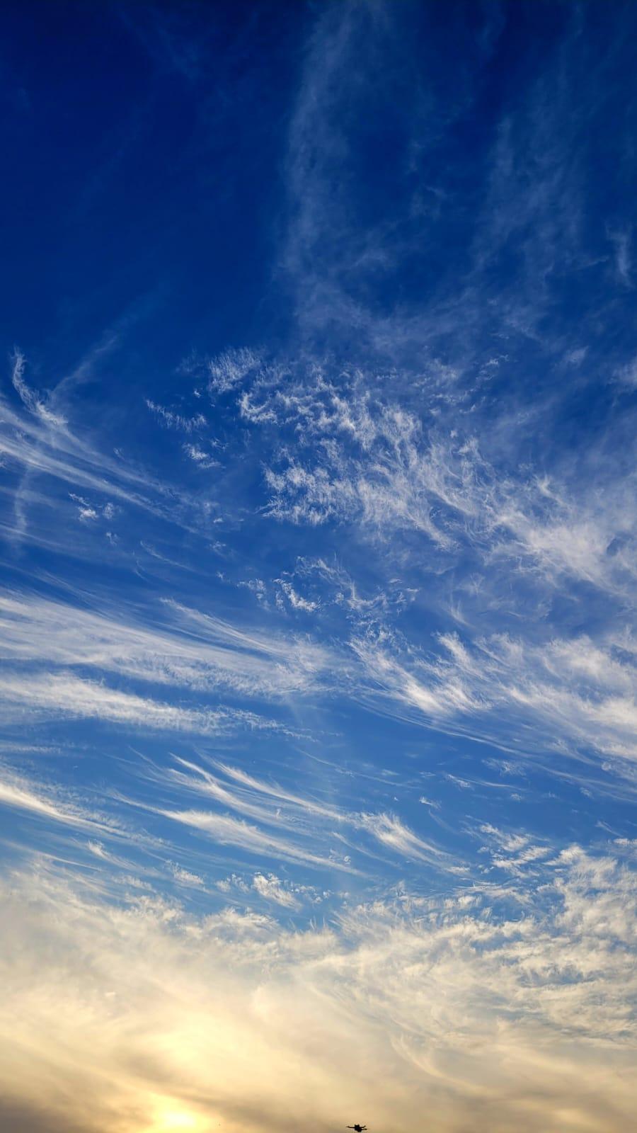 Wispy clouds streaking across a deep blue sky at golden hour